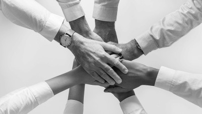 A group of employees with their hands in a circle showing teamwork.