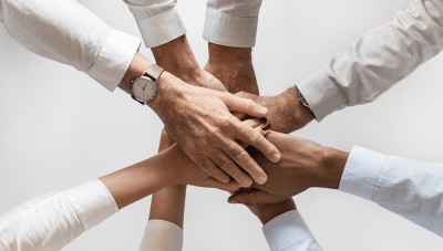 A group of employees with their hands in a circle showing teamwork.